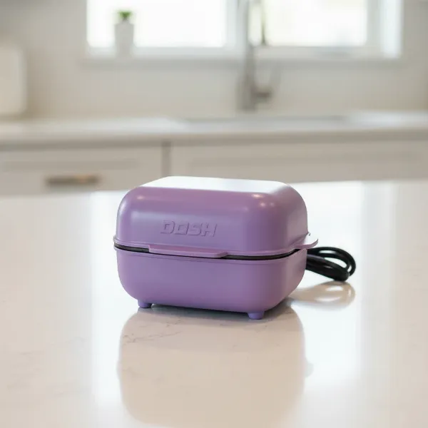 A compact Dash Express Mini Cupcake Maker on a kitchen counter, ready for quick baking.